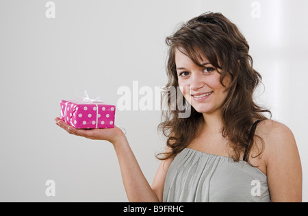 Teenager girl cheerfully gift smile presents semi-portrait people teenager-girl teenagers happily shows giving offers gets Stock Photo