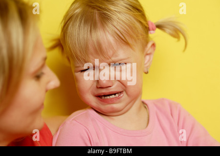 Upset Baby Girl Cries And Looks With Unsatisfied Expression Stock Photo