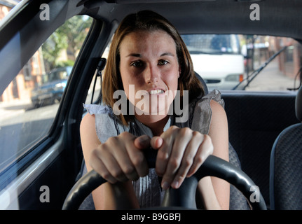 A nervous female learner driver sits gripping the steering wheel of a car Stock Photo