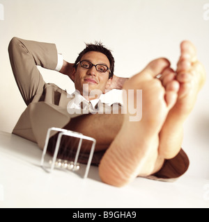 Managers barefoot feet puts up manager-game relaxation series desk table people man 30-40 years sitting  leans back feet Stock Photo