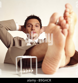 Managers barefoot feet puts up manager-game relaxation series desk table people man 30-40 years sitting  leans back feet Stock Photo