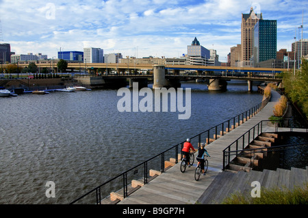 Couple cycling along the Riverwalk in downtown Milwaukee Wisconsin Stock Photo