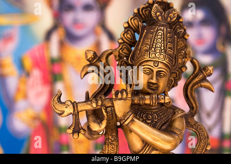 Metal Statue of Indian God Krishna Playing Flute with Colourful Indian Background Stock Photo