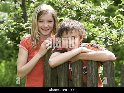 teenagers boy girl fence rested smiling semi-portrait  12-13 years arm rested resting gaze camera brother vacation leisure time Stock Photo