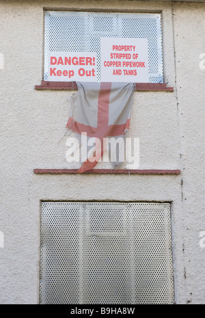 A tattered St George flag hanging from an empty houses on a derelict housing estate near Wolverhampton in the the West Midlands Stock Photo