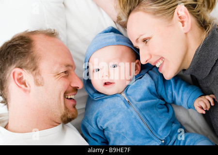 Baby laying between dad and mom Stock Photo