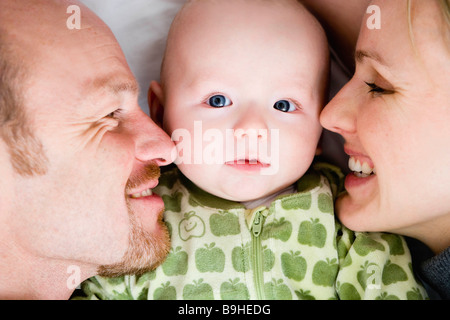 Baby laying between dad and mom Stock Photo