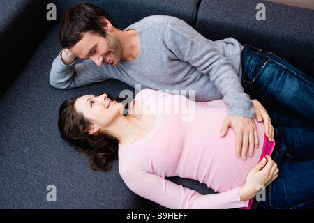 Pregnant woman and man laying on couch Stock Photo