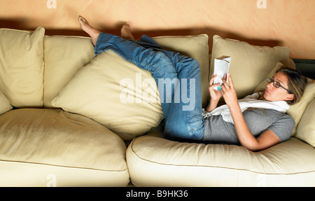 Woman reading a book on sofa Stock Photo