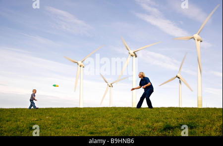 Man,  boy play Frisbee at Wind Turbines Stock Photo