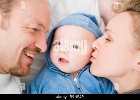 Baby laying between dad and mom Stock Photo