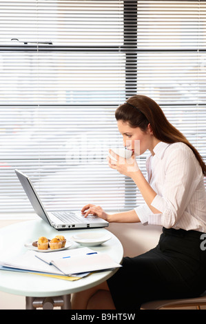 Woman sitting with laptop at cafe table Stock Photo