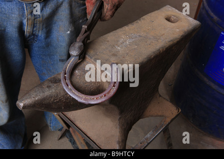 Farrier making horseshoes on his anvil Stock Photo