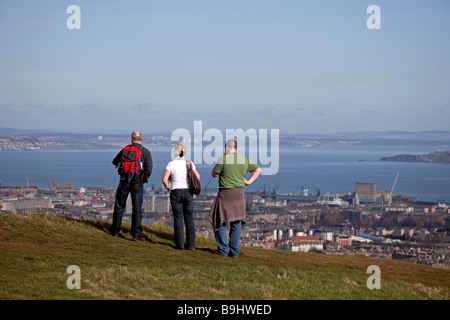Two Males and female looking out over the city of Edinburgh Scotland, UK, Europe from above Holyrood Park Stock Photo