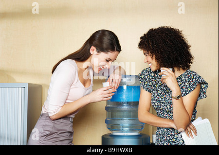 Two women laughing by water cooler Stock Photo