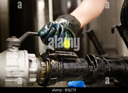 Roller employee in the color warehouse controlling the feed line of black color to the color containers direct to the printing  Stock Photo