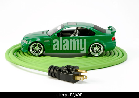 A green automobile car on a green coiled electrical extension power cord with one plug Stock Photo