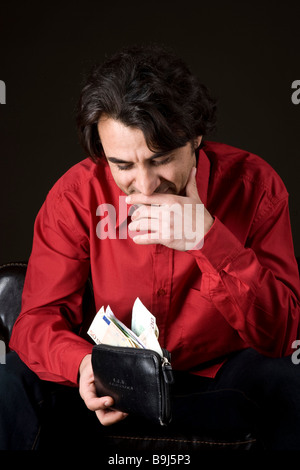 Young man happily looking into his full wallet Stock Photo