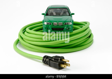 A green automobile car on a green coiled electrical extension power cord with one plug Stock Photo