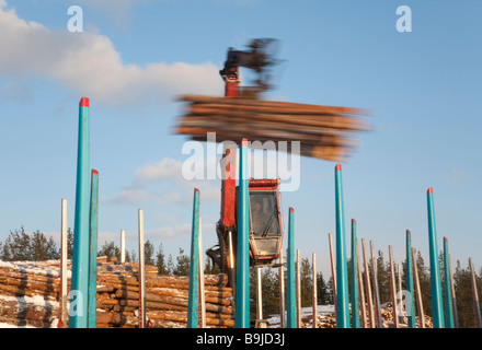Log truck driver using truck crane and loading logs to cargo log train cars at railroad depot at Winter . Finland Stock Photo