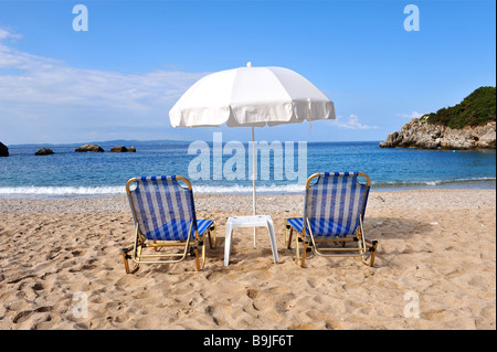 Two empty sun loungers and a parasol on the deserted beach in Sarakina, Lefkada Stock Photo