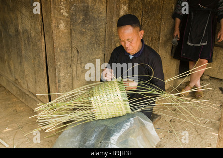 Black Hmong man weaving a basket in his home near Sapa Vietnam Stock Photo