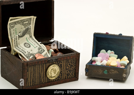 Two small treasure chests, one filled with money, another with heart-shaped candy Stock Photo