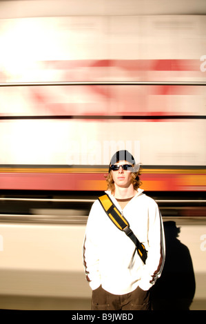 A young man stands as a train goes by behind him in Whitefish, MT. Stock Photo