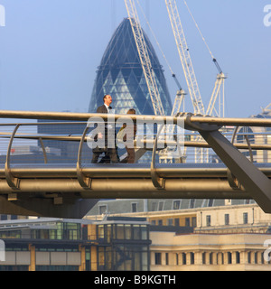 A city business man walks across the London Millennium bridge in the city of london uk Stock Photo
