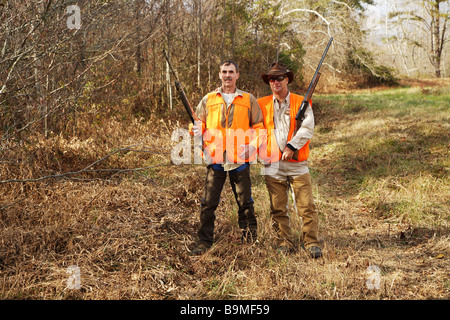 Two hunter in orange safety vests holding shotguns