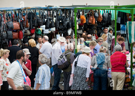 Tourists hunting for a bargain in popular Los Cristianos Sunday market with leather goods on display Tenerife Canary Islands Stock Photo