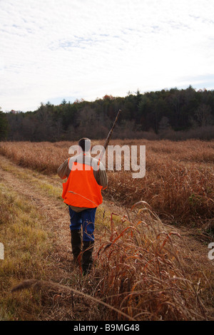 Hunter walking a field in search of game Shotgun and orange vest