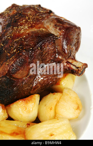 A roasted leg of lamb on a plate with roast potatoes. Stock Photo