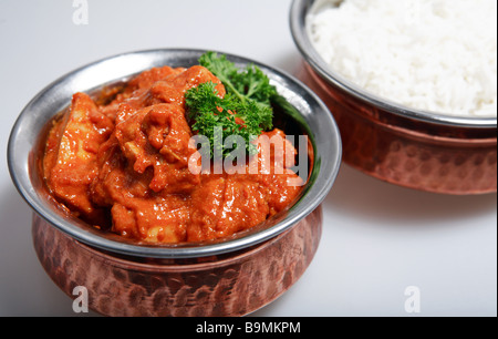 Serving bowls with a red Thai chicken curry,cooked with coconut milk and mango  and plain white basmati rice. Stock Photo