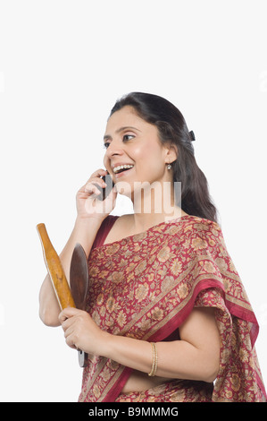 Woman holding a rolling pin and talking on a mobile phone Stock Photo