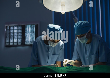 Two female surgeons performing a surgery in an operating room Stock Photo