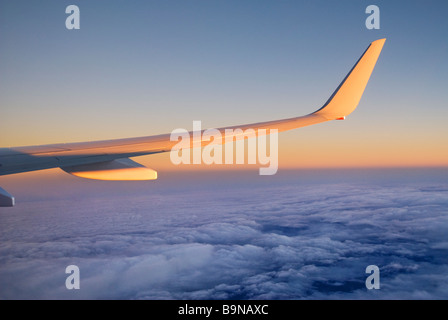 View through airliner window high above clouds at sunrise