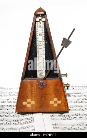 Old German metronome sits on top of sheet music. Stock Photo