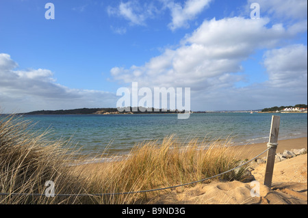 STUDLAND, DORSET, UK - MARCH 14, 2009:  View across beach with Marram grass and fence post with land on the horizon at Shell Bay Stock Photo