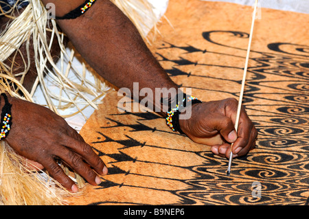 Local artist paints traditional motifs on the bark of the Khambouw tree, Lake Sentani area, West Papua, Indonesia Stock Photo