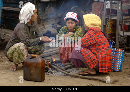 Burmese day labourer sitting on small fire at the ferry station of Mandalay Myanmar Stock Photo