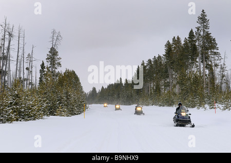 Touring snowmobilers on Norris Canyon Road in Yellowstone National Park Wyoming USA in winter Stock Photo