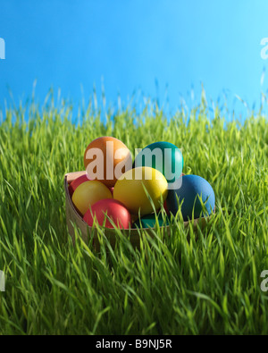 colored Easter eggs in basket in the the grass Stock Photo