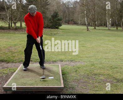 Golfer hitting a ball from a temporary tee. Stock Photo