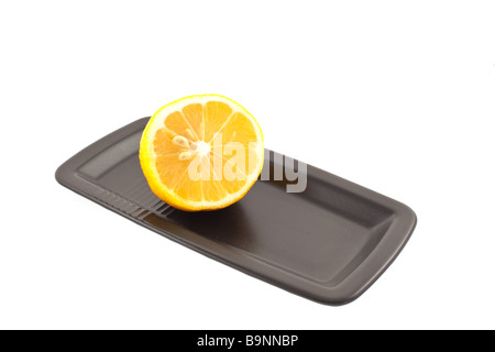 half of lemon on a black square plate on a white background Stock Photo