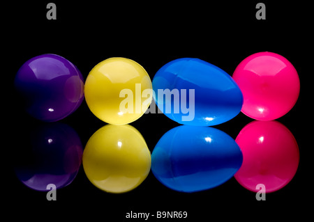 Four colorful plastic Easter eggs on a reflective surface Stock Photo