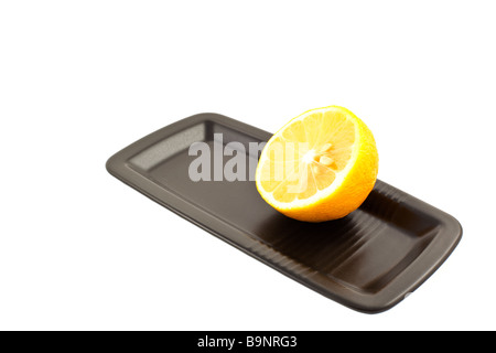 half of lemon on a black square plate on a white background Stock Photo