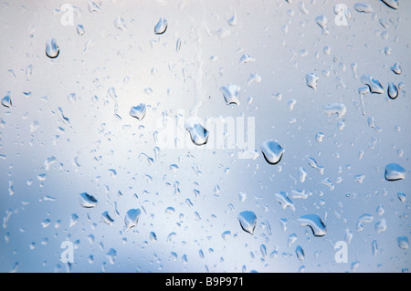 Rain drops on a window looking out to a brightening sky. Stock Photo