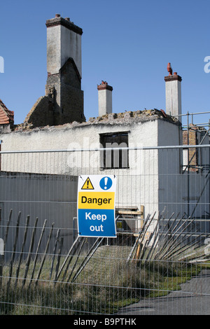 Warning sign attached to fencing outside a burnt out derelict building. It reads ' Danger Keep Out' Stock Photo