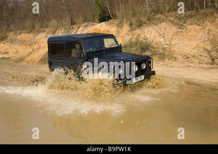 A Land Rover Defender drives through a flood Stock Photo